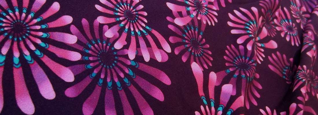 Andromeda Meadow 02 fabric. Vibrant pinky purple spirals with turquoise detail on dark purple background.